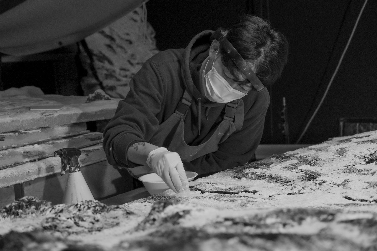 An artist dressing the surface of a snow set